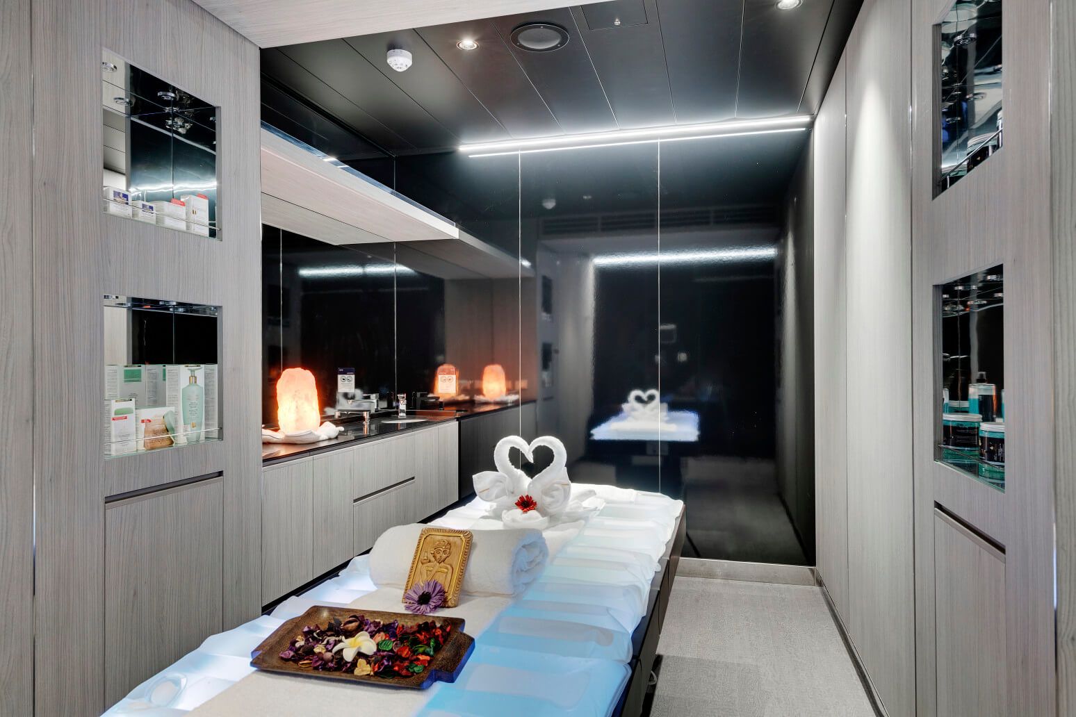 Ein eleganter Wellnessraum mit Massagebett, Deko, Naturstein und Pflegeprodukten. Beruhigende Atmosphäre.